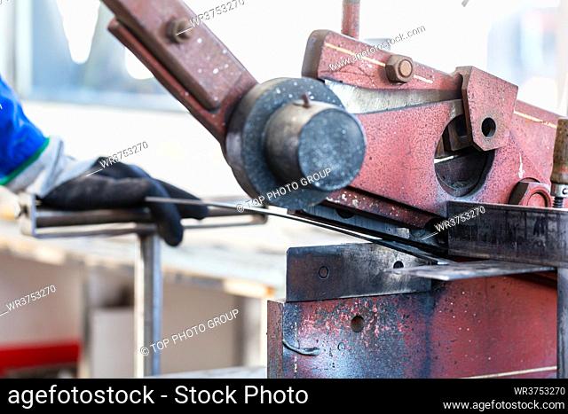 Craftsman cutting Metal with skip in workshop