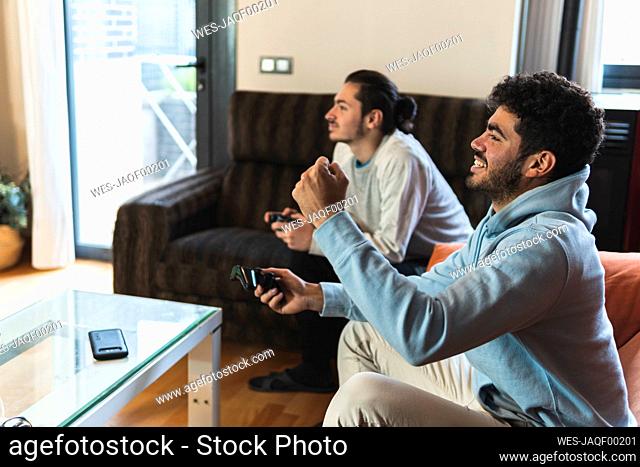 Cheerful friends playing video game in living room at home