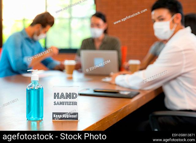 Signage of Hand sanitizer alcohol gel in meeting room with background of Asian team business people working and brainstorm