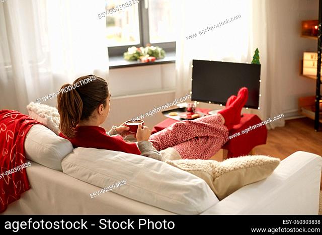 woman watching tv and drinking coffee on christmas