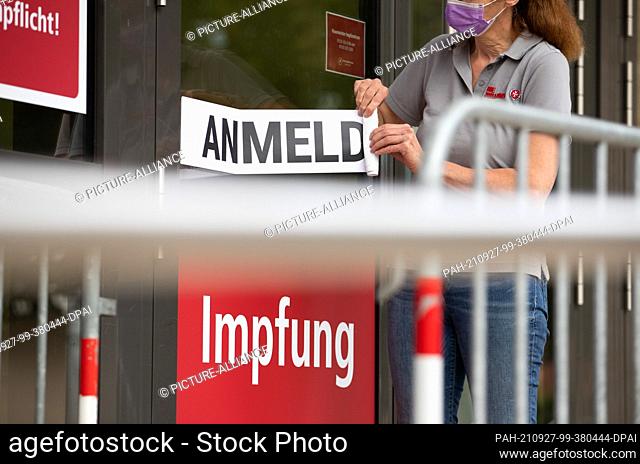 27 September 2021, Lower Saxony, Osnabrück: An employee removes signs and posters from the exterior of the city's Immunization Center
