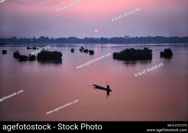 Muang Khong, Laos, Asia - Looking from Don Det Island at a wooden canoe that is silhouetted against the sunrise over the Mekong River