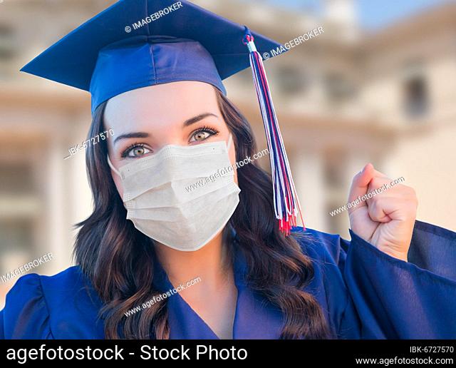 Female graduate in cap and gown wearing medical face mask