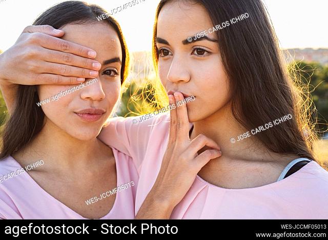 Sisters covering each other's eye and mouth