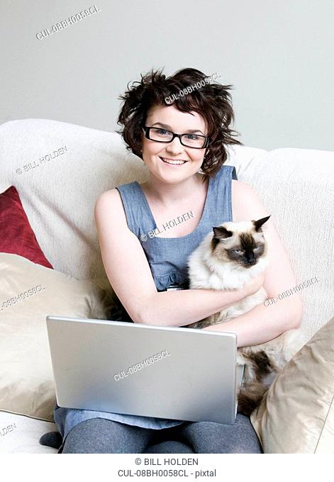 Female holding a cat and a laptop