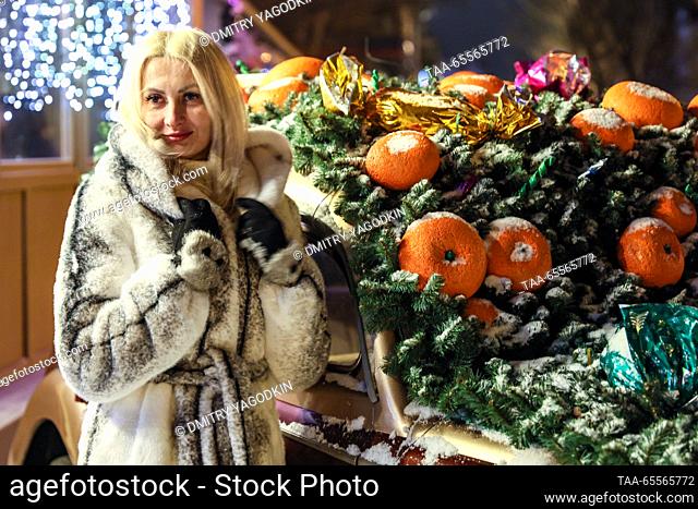 RUSSIA, DONETSK - DECEMBER 8, 2023: A woman poses for a photograph by a car decorated for the holiday season. Dmitry Yagodkin/TASS