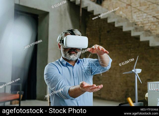 Architect wearing virtual reality simulator gesturing with wind turbine design at construction site
