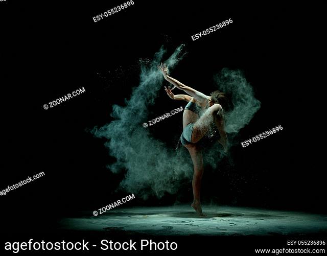 Graceful girl wearing top and shorts in white dust cloud profile shot in the dark room