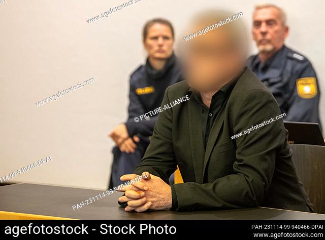 14 November 2023, Bavaria, Augsburg: Guarded by two police officers, a defendant sits in the dock at the regional court. Two men are once again on trial in...