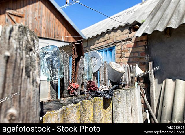 On the old wooden fence in the Russian Outback dried glass jars and aluminum cookware
