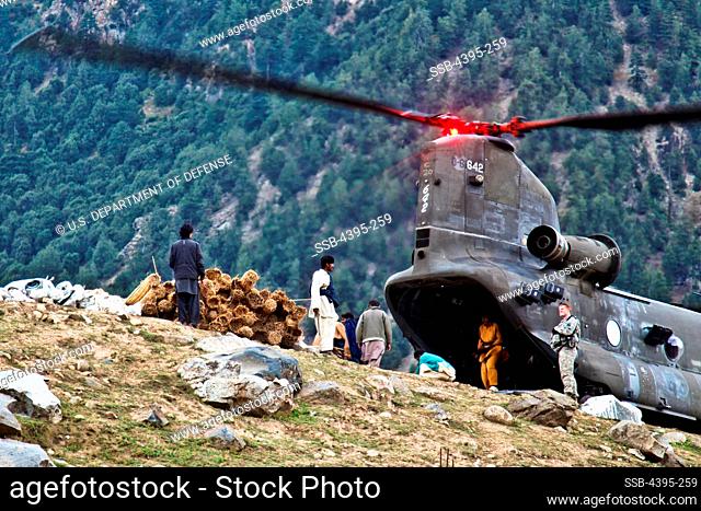 Pakistani men unload construction supplies delivered by a U.S. Army CH-47 chinook helicopter from 16th Combat Aviation Brigade to rebuild flood victims homes in...