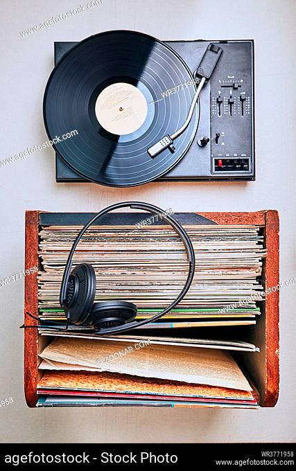 Stack of black vinyl records, turntable vinyl player and headphones. Classic stereo set. Candid people, real moments, authentic situations