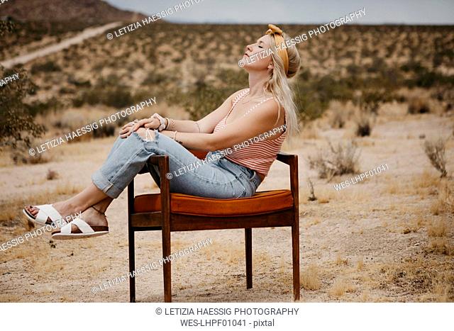 Woman sitting on a chair in desert landscape, Joshua Tree National Park, California, USA