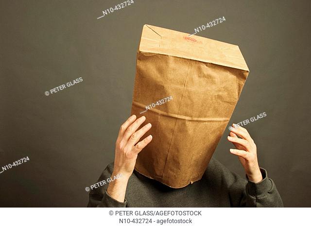 Man whose head is covered with a paper bag and whose hands are up in the air