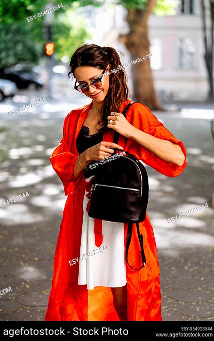 Girl posing for the camera with a female bag on the street