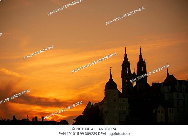 15 October 2019, Saxony, Meißen: The setting sun colors the sky behind the cathedral to Meissen orange-red. The cathedral is dedicated to St