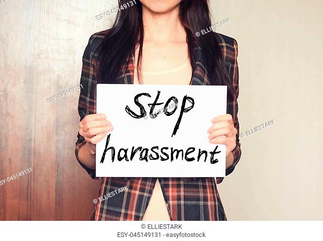 Girl holds a paper sheet with text stop harassment against sexual abusing