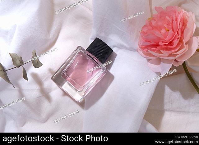 bottle of perfume and flower on white sheet