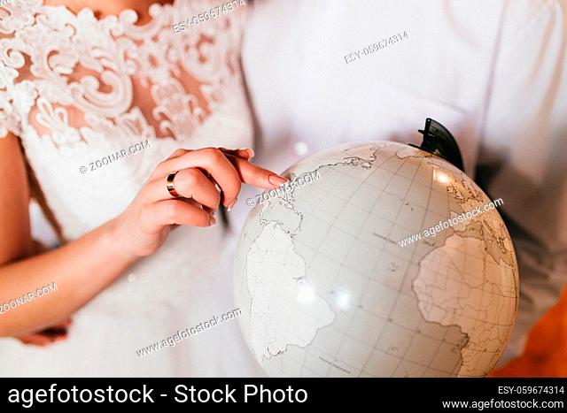 Bride is showing place on the globe. High quality photo