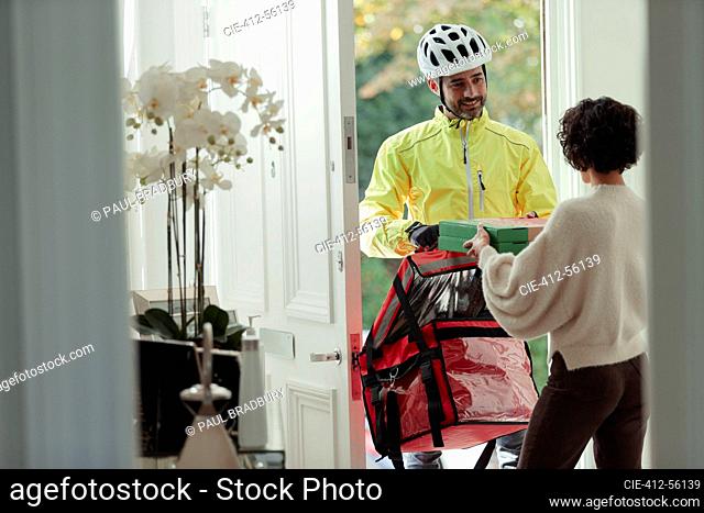 Friendly courier delivering pizza to woman at front door