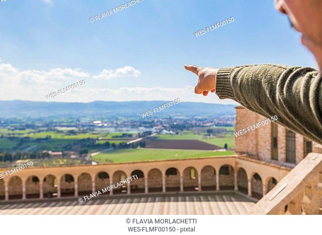 Italy, Umbria, Assisi, man's hand pointing at the fields surrounding the Basilica of San Francesco d'Assisi