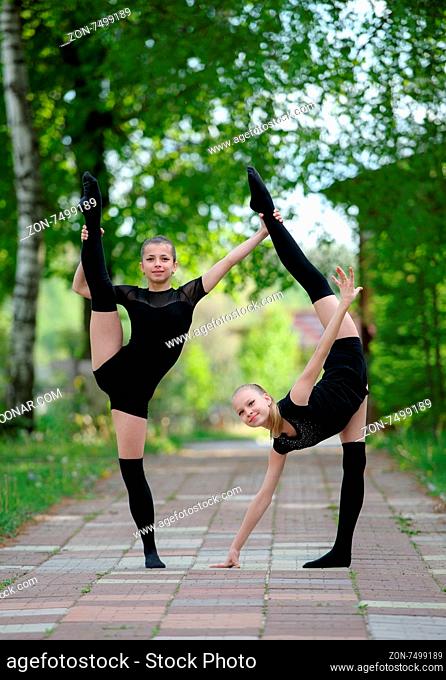 Two teen rhythmic gymnasts are showing their stretching and flexibility