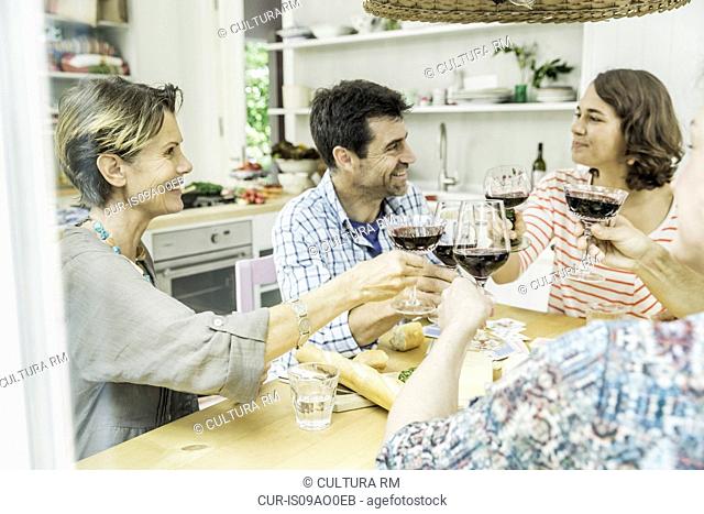 Adult friends making a toast with wine at dining table
