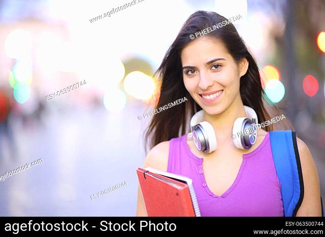 Front view portrait of a happy student posing in the street looking at camera