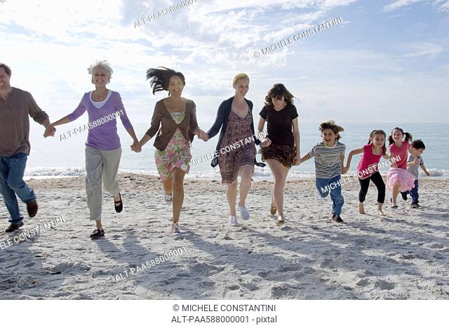 Group of people holding hands and running on beach