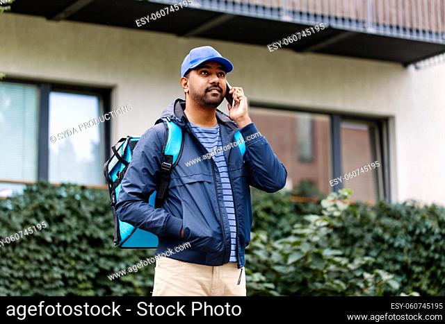 indian delivery man with bag calling on smartphone