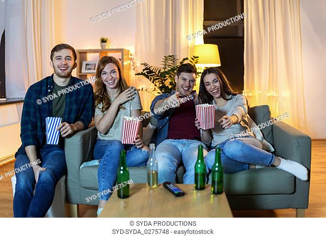 friends with beer and popcorn watching tv at home