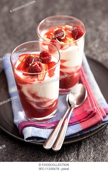 Two glasses of yogurt with fruit coulis, fresh red berries lemon zest