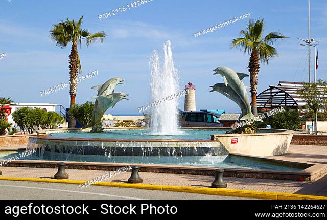 Menton, France - May 03, 2021: Summer Pre Season Spring Atmosphere with Dolphins Water Fountain. Dolphin Dauphin, Sea, Harbour, Hafen, Meer, Strand, Tourism