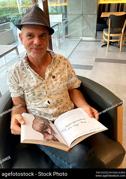 PRODUCTION - 17 January 2022, Thailand, Bangkok: German author Tom Vater is leafing through his book ""Sacred Skin"" about the sacred tattoo art Sak Yant in a...