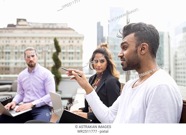 Business people discussing while sitting at rooftop restaurant