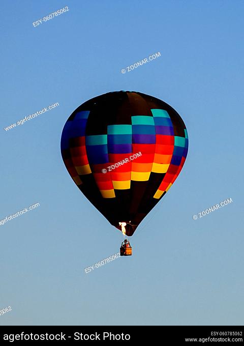 A colorful hot air balloon shooting a flame floats in the sky in north Idaho
