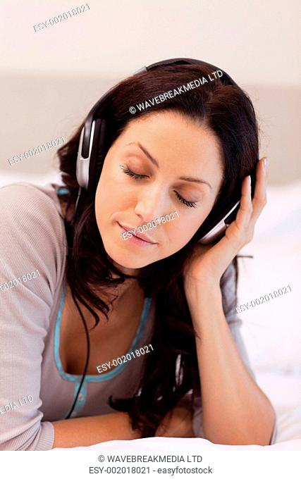 Young woman laying on her bed enjoying music