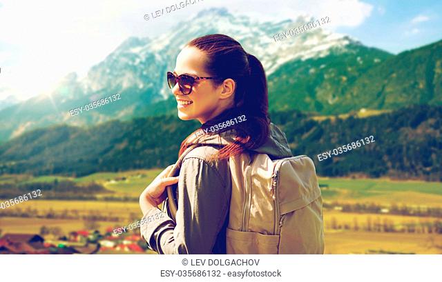 travel, tourism and people concept - happy young woman with backpack over alps mountains background