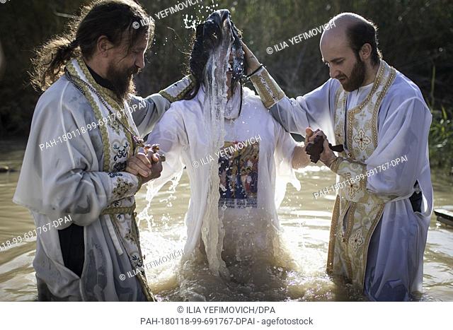 Two priests baptise an Orthodox Christian pilgrim during the feast of the Epiphany at the West Bank baptismal site of Qasr el Yahud, in the Jordan River Valley