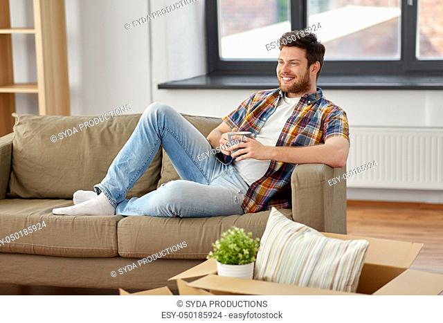 man with boxes and drinking coffee at new home