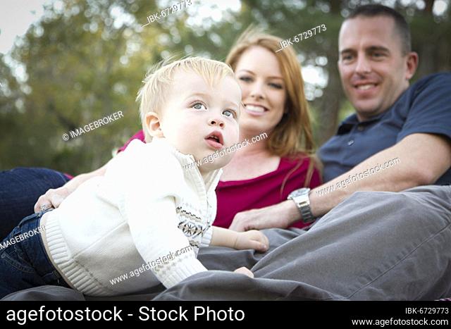 Cute child boy looks up to the sky as young parents smile