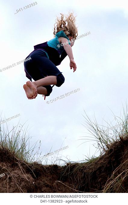 child girl jumping from sand dune