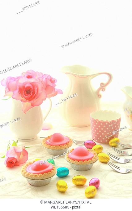 Easter table with sweet eggs, pink roses and fresh cakes