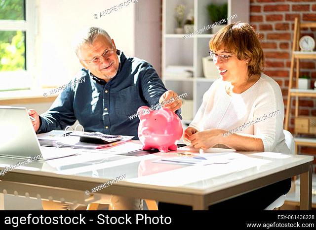 Young Man Looking At Woman Inserting Coin In Piggybank