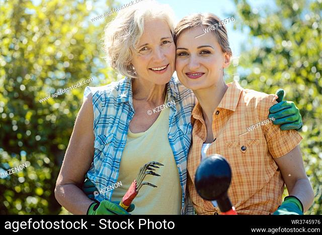 Woman gardening together in summer looking at each other
