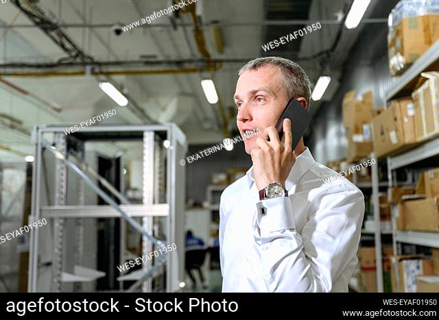 Businessman talking on smart phone in factory
