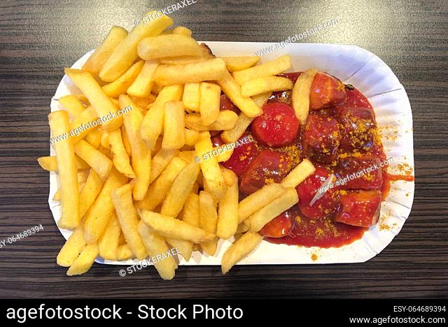 currywurst - typical german fast food dish of sliced pork sausage with curry ketchup sauce and french fries