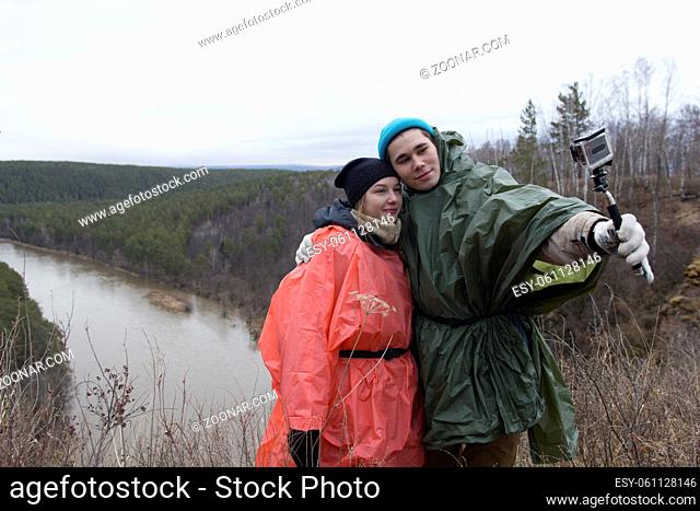 Young couple making selfie in the hillside to the river, telephoto shot
