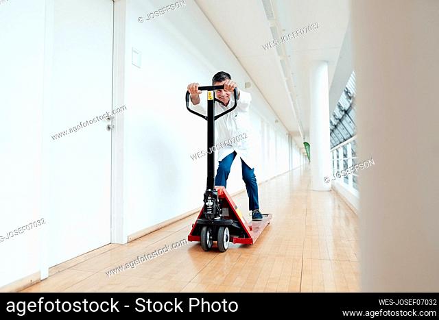 Scientist playing with pallet jack in corridor