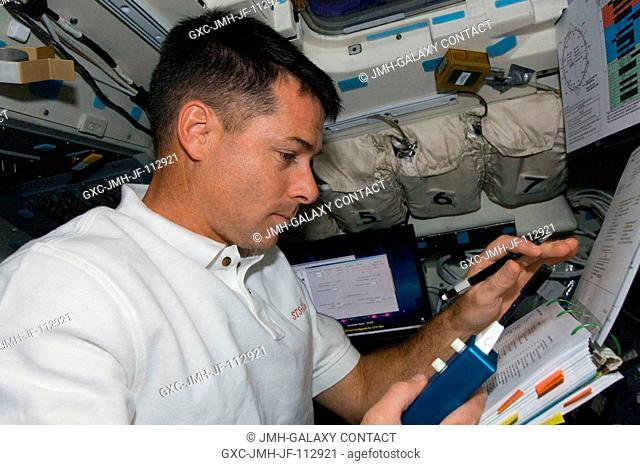Astronaut Shane Kimbrough, STS-126 mission specialist, looks over a checklist on the aft flight deck of Space Shuttle Endeavour while docked with the...